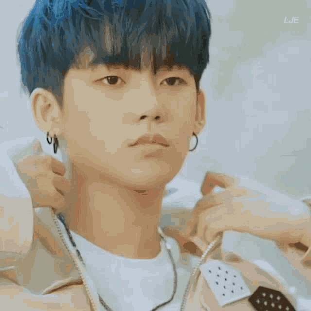 a young man with blue hair and earrings is being adjusted by a woman .