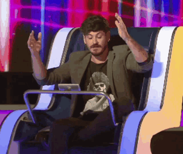 a man in a suit is sitting in a chair with his arms in the air