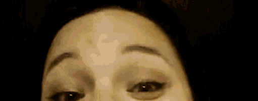 a close up of a woman 's face with a black background and a blurred background .