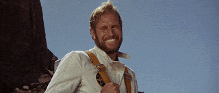 a man with a beard wearing suspenders and a white shirt is smiling