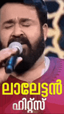 a man with a beard is singing into a microphone in a pink shirt .