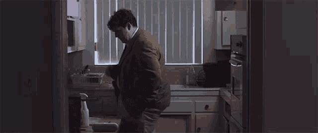 a man in a brown suit is standing in a kitchen with a box that says 500 on it