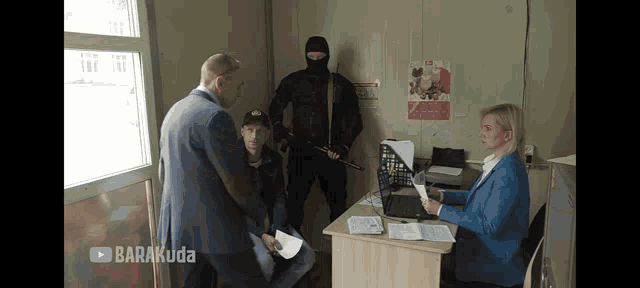 a man in a mask is standing in front of a woman in a blue suit and a man in a suit