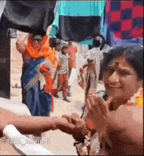 a woman in a sari is shaking hands with a man in a crowd of people .