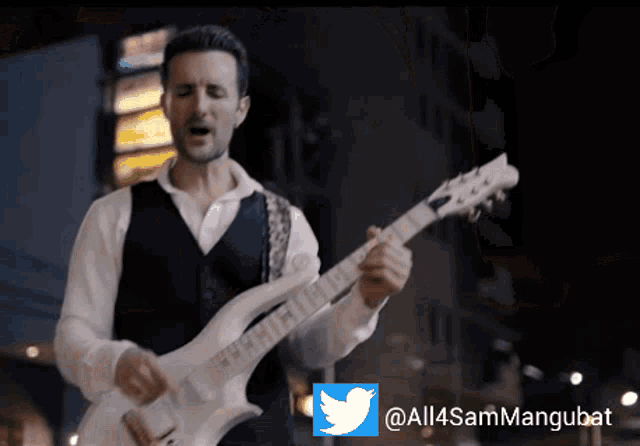 a man singing while playing a guitar with a twitter logo in the corner