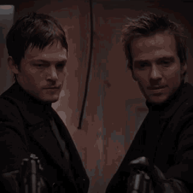 two men standing next to each other with guns