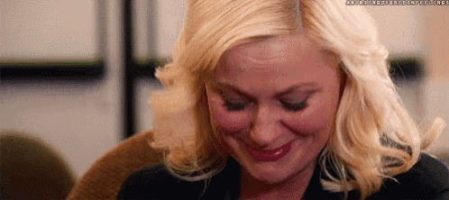 a woman with blonde hair is smiling with her eyes closed and red lipstick on her lips .