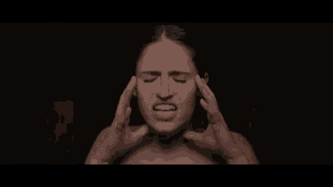 a woman without a shirt is screaming with her mouth open in the dark .