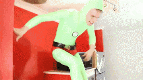 a man in a green superhero costume is standing in front of a microwave