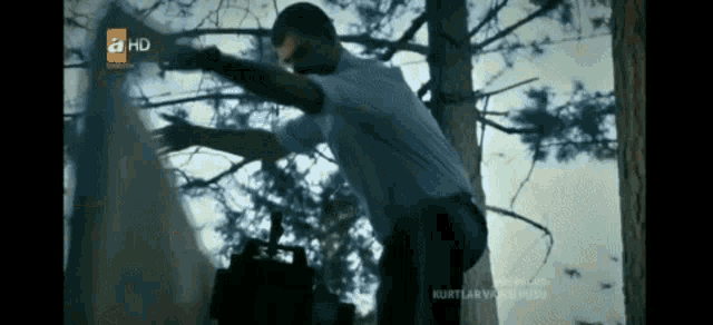 a man in a white shirt is standing next to a tree with a hd logo on the bottom