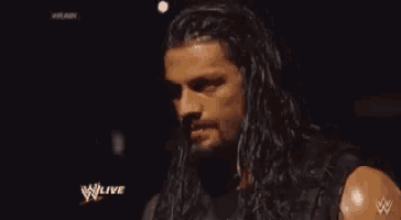 a close up of a man with long hair and a beard on a wrestling show .