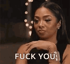 a woman is making a funny face and saying `` fuck you '' with her hand on her chin .