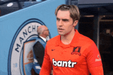 a man wearing an orange shirt that says bantr