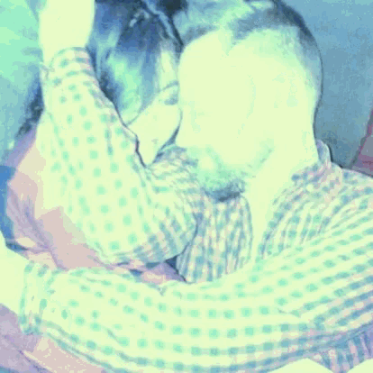 a man in a plaid shirt is hugging another man
