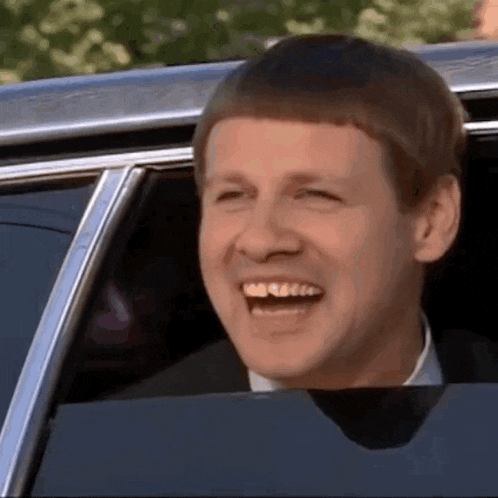 a man is smiling while sitting in a car .