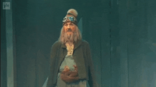 a man with a beard and overalls is dancing on a stage while holding a squirrel .