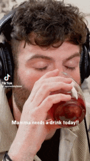 a man wearing headphones is drinking from a glass with the words mamma needs a drink today