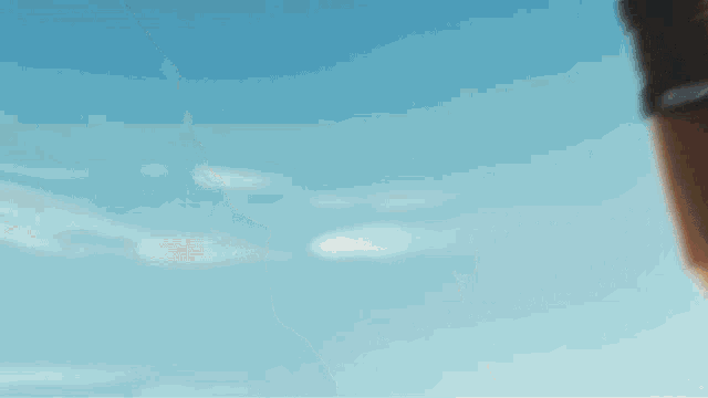a blurry picture of two people holding hands against a blue sky .