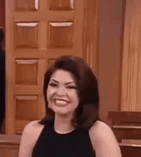 a woman in a black dress is smiling and looking at the camera .