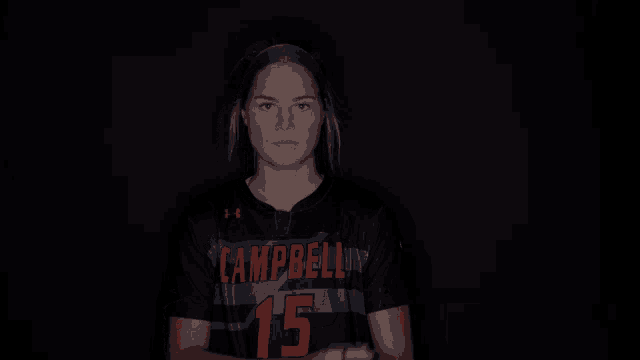 a girl wearing a campbell jersey stands with her arms crossed