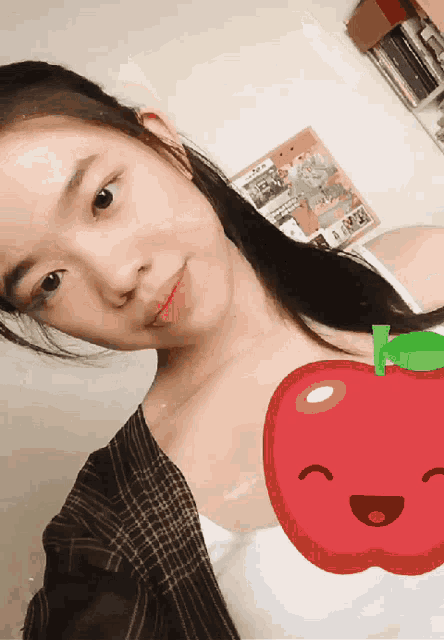 a girl taking a selfie with a red apple in the background