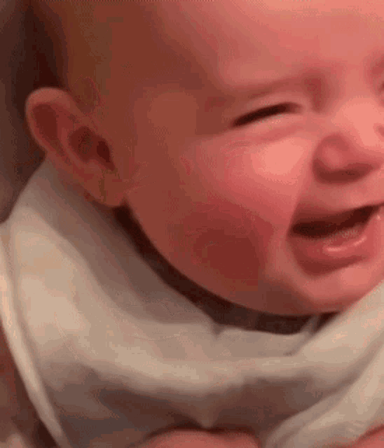 a close up of a baby crying with his eyes closed .