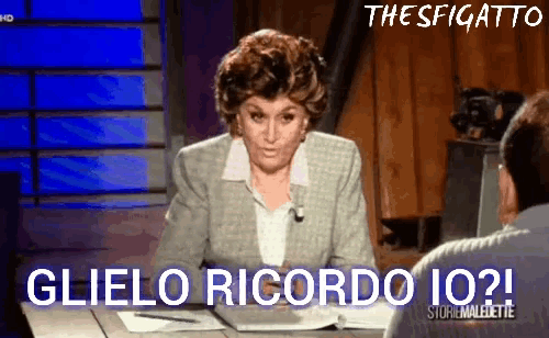 a woman sitting at a desk with the words glielo ricordo io written on the bottom