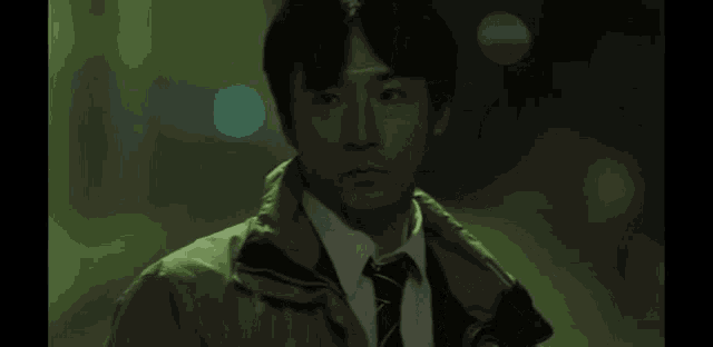 a man in a green jacket and tie is looking at something