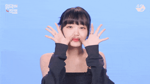 a woman making a funny face with her hands in front of her face with a blue background