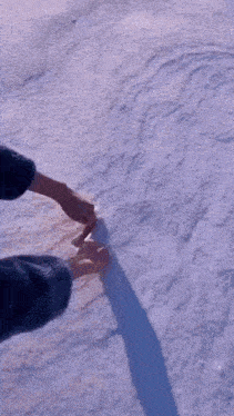 a person is drawing a heart shape in the snow .