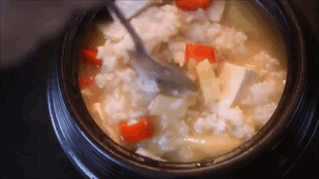 a pot filled with rice and vegetables is being stirred with a spoon