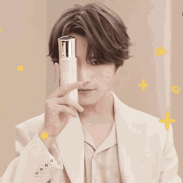 a man in a white suit holds up a bottle that says shiseido