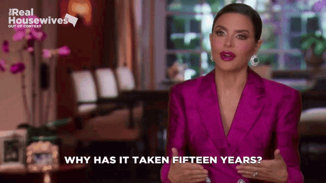 a woman in a pink suit is talking about why has it taken fifteen years