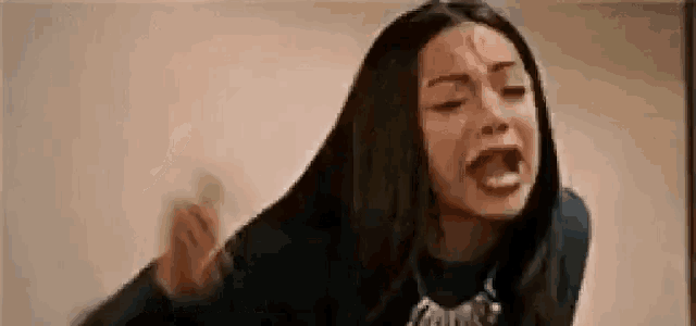 a woman with long hair is crying and screaming with her mouth wide open .