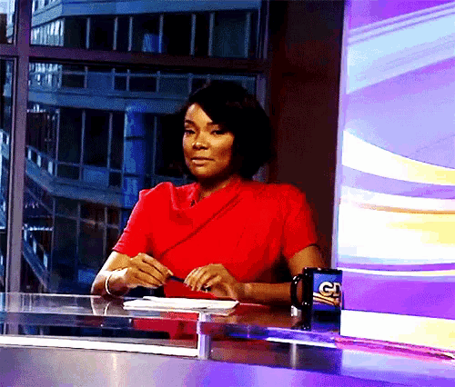 a woman in a red shirt sits at a desk with a fox news mug