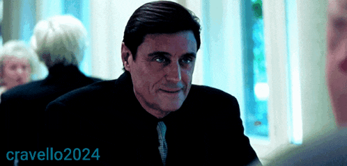 a man in a black suit and tie is smiling in front of a sign that says cravello2024