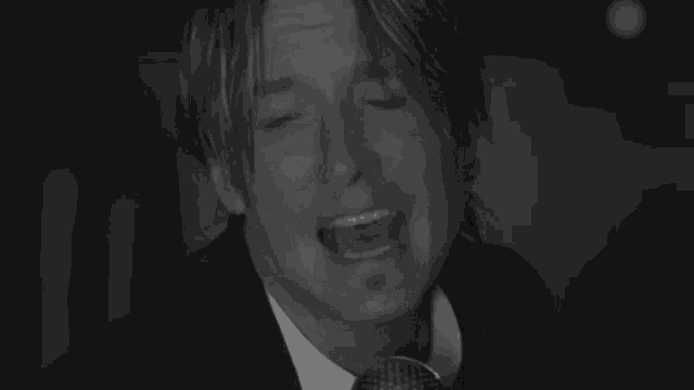a man in a suit and tie is singing into a microphone in a black and white photo