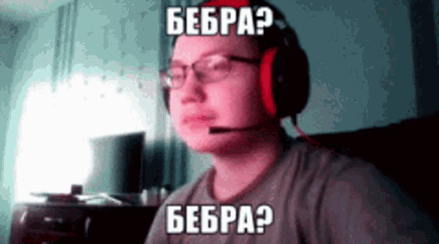 a man wearing headphones and glasses is sitting in front of a computer with a microphone on his head .