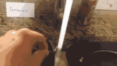 a person is washing a pot in a sink with a sign that says yakibacon32 on it