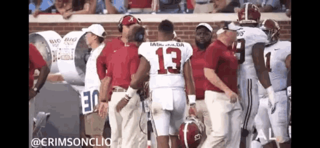 a football player with the number 13 on his jersey is talking to a coach on the sidelines .