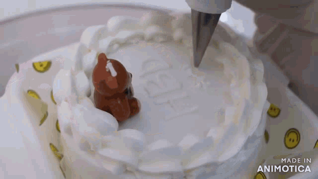 a cake is being decorated with whipped cream and a brown teddy bear
