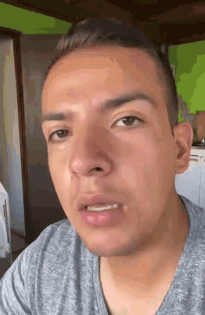 a man is making a funny face while wearing a grey shirt .