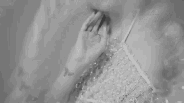 it is a black and white photo of a woman applying perfume to her neck .
