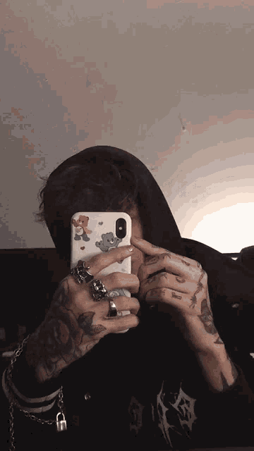 a man taking a picture of himself with a teddy bear on his phone