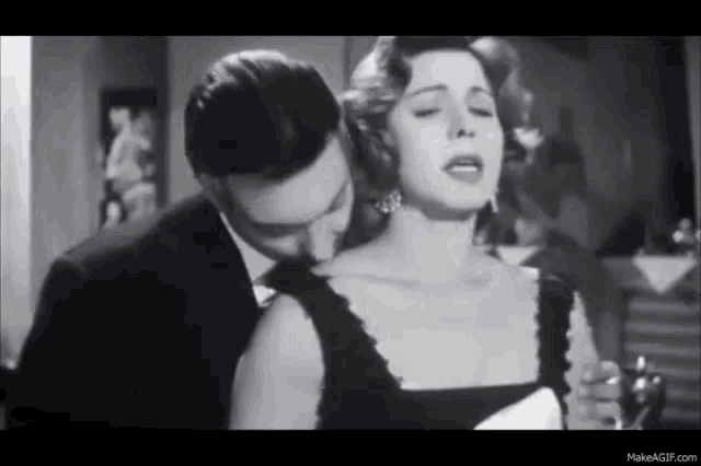 a man is kissing the neck of a woman in a black and white photo .