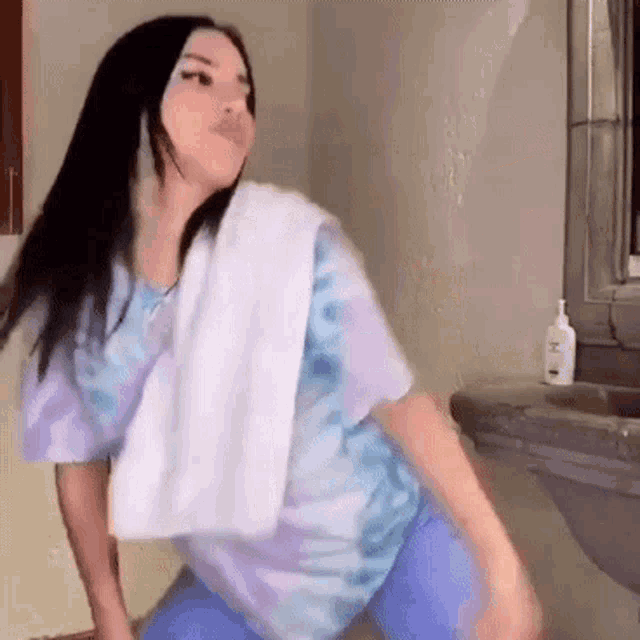 a woman in a tie dye shirt is dancing in a bathroom .