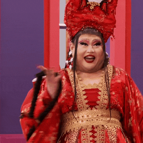 a woman in a red and gold costume is holding a black whip