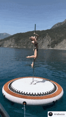 a woman in a bikini is standing on a pole in the water ..
