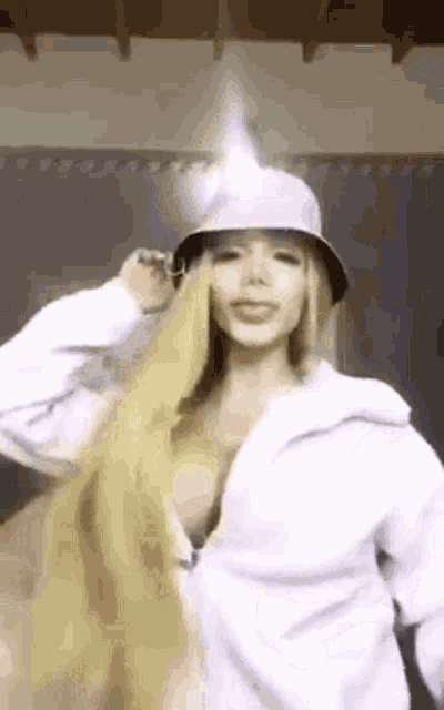 a woman with long blonde hair is wearing a bucket hat and a white shirt .