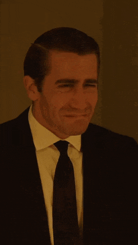 a man in a suit and tie is looking at the camera with a serious look on his face .